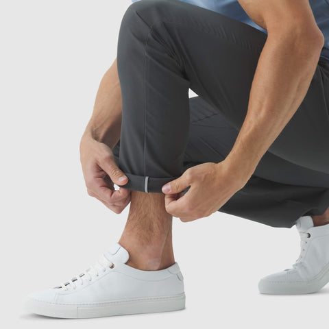 Man wearing Jetsetter Tech Pant Slim Fit showing reflective tape detail with white sneakers.