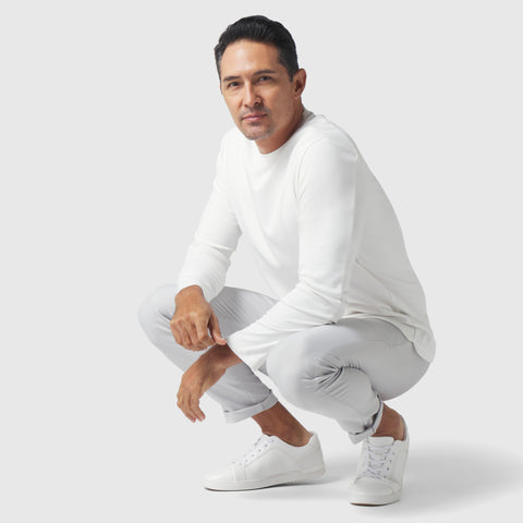 Man wearing white Precision Long Sleeve Tee made from organic cotton, showcasing breathable, wrinkle-resistant fabric.