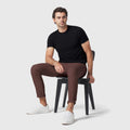 Jetsetter Tech Pant Slim Fit in brown worn by a seated person, featuring a modern travel-friendly design.