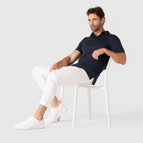 Jetsetter Tech Pant Slim Fit in white worn by seated model, highlighting travel-friendly and wrinkle-free features.