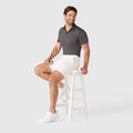 Man wearing Jetsetter Tech Short in white, sitting on a stool, showcasing a comfortable and consistent fit.