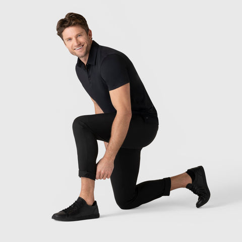 Man wearing Jetsetter Tech Pant Slim Fit in black, demonstrating flexibility and style.