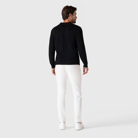 Man wearing black Legacy Polo Sweater and white pants, rear view.