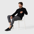 Legacy Polo Sweater in black, worn by a seated model, showcasing refined knitwear style.