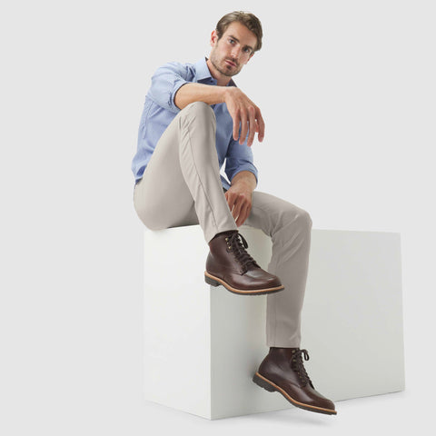 Man wearing Jetsetter Tech Pant Slim Fit, light gray, with boots in a casual pose.