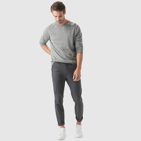 Slim fit Jetsetter Tech Pant in dark hue, worn by a model with light grey sweater and white sneakers.